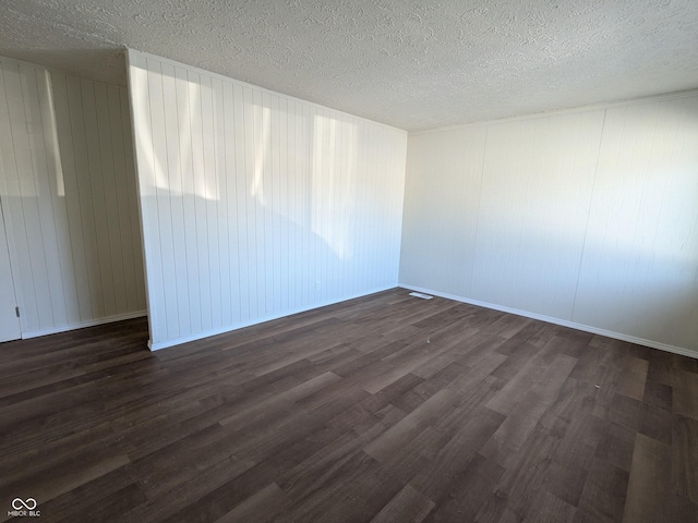 unfurnished room with dark wood-type flooring and a textured ceiling