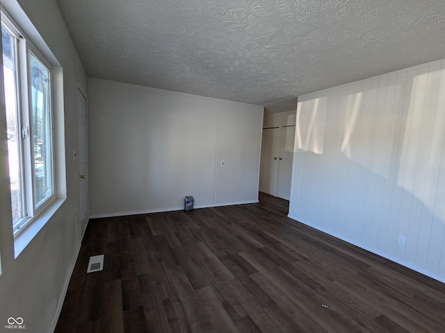 unfurnished room featuring a textured ceiling and dark hardwood / wood-style flooring