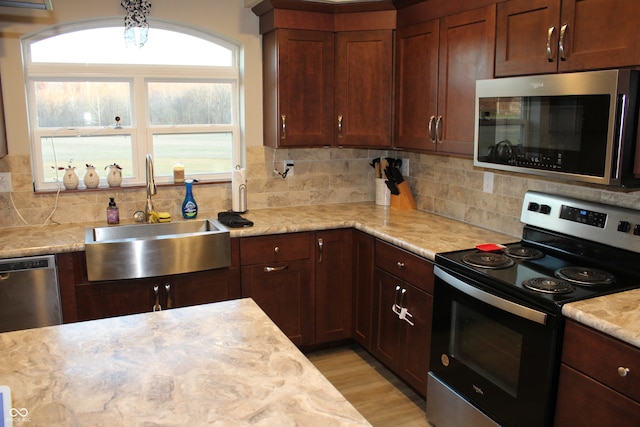 kitchen featuring sink, light stone counters, appliances with stainless steel finishes, tasteful backsplash, and light hardwood / wood-style flooring