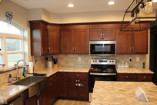 kitchen featuring stainless steel appliances, light stone countertops, sink, and decorative backsplash