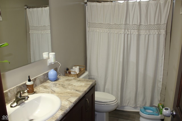 bathroom with toilet, vanity, hardwood / wood-style flooring, and curtained shower