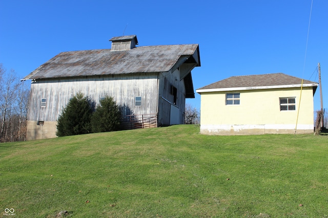 back of property featuring a lawn and an outbuilding