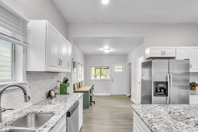 kitchen featuring white cabinetry, sink, light hardwood / wood-style flooring, decorative backsplash, and appliances with stainless steel finishes