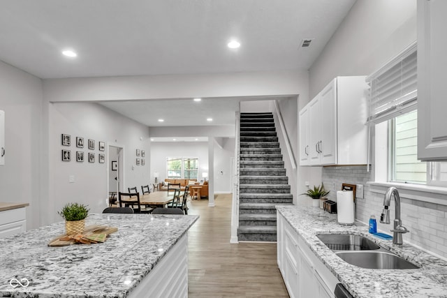 kitchen featuring white cabinets, a center island, sink, and light hardwood / wood-style flooring