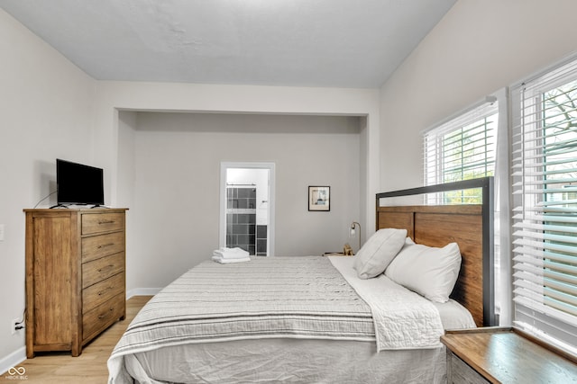 bedroom with light wood-type flooring and ensuite bathroom