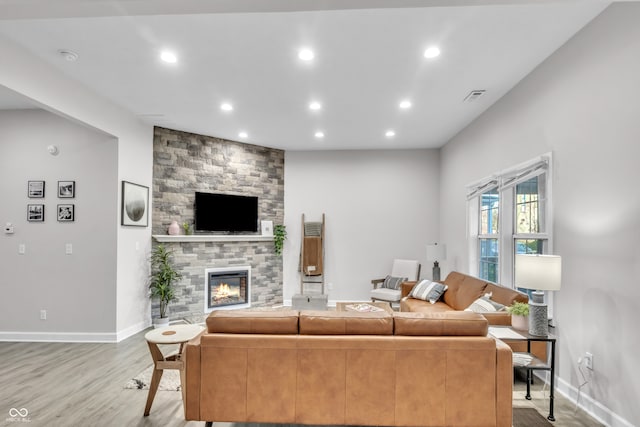 living room featuring light hardwood / wood-style flooring and a stone fireplace