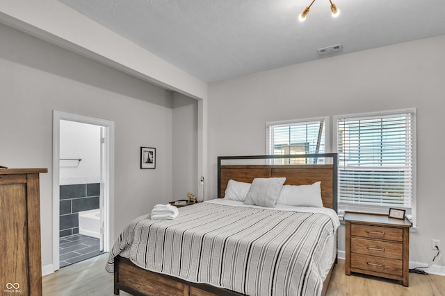 bedroom with light wood-type flooring and connected bathroom