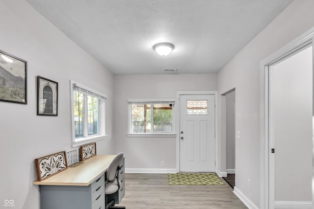 entryway with a textured ceiling and light wood-type flooring