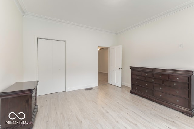 unfurnished bedroom featuring crown molding, light hardwood / wood-style flooring, and a closet