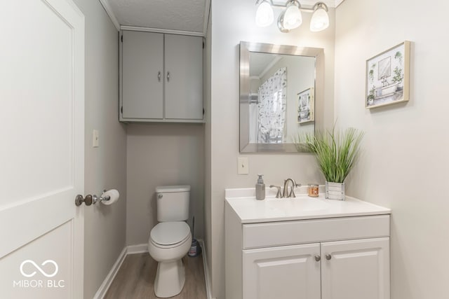 bathroom featuring wood-type flooring, toilet, a textured ceiling, and vanity