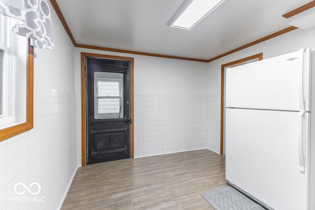 foyer with hardwood / wood-style flooring, tile walls, and crown molding