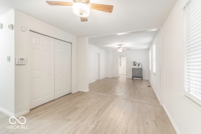 hall with light hardwood / wood-style floors and a textured ceiling