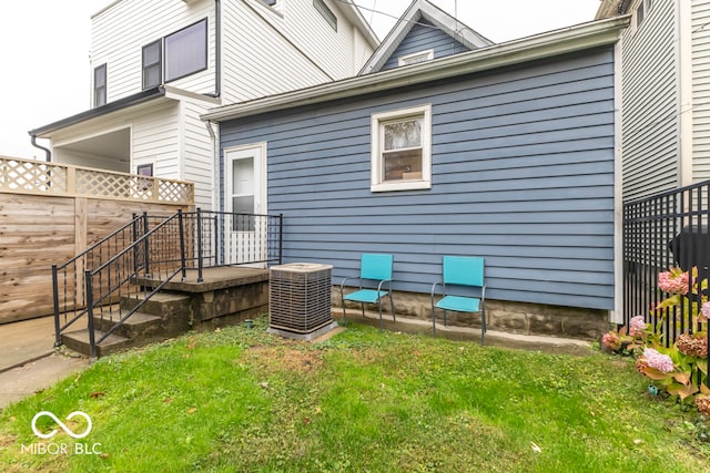 rear view of house with central AC and a yard