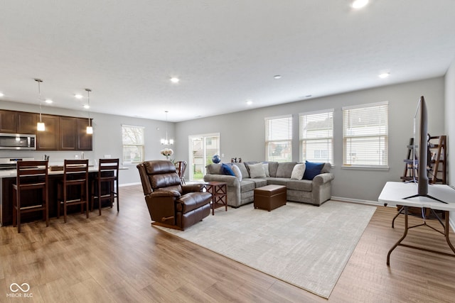 living room with light wood-type flooring and an inviting chandelier