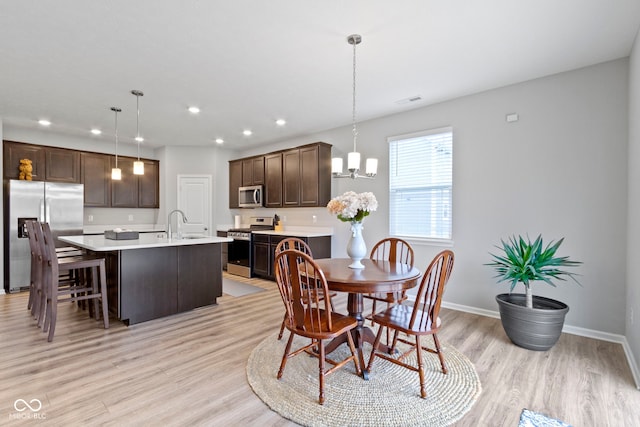 dining area with light wood-type flooring, a notable chandelier, and sink