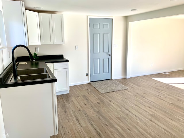 kitchen with white cabinetry, sink, and light hardwood / wood-style floors