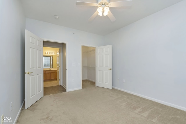 unfurnished bedroom with light carpet, a closet, a spacious closet, and ceiling fan