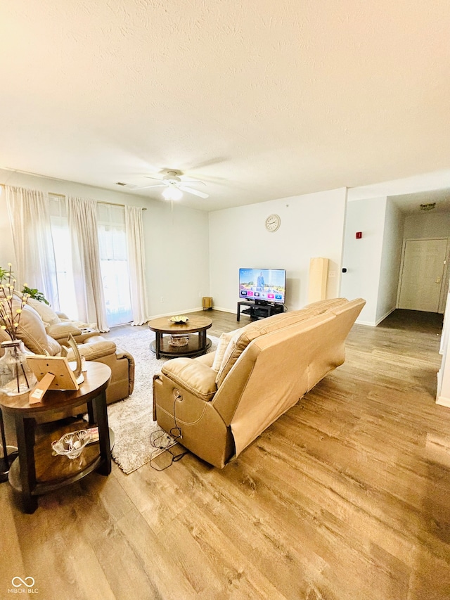 living room featuring a textured ceiling, light hardwood / wood-style floors, and ceiling fan