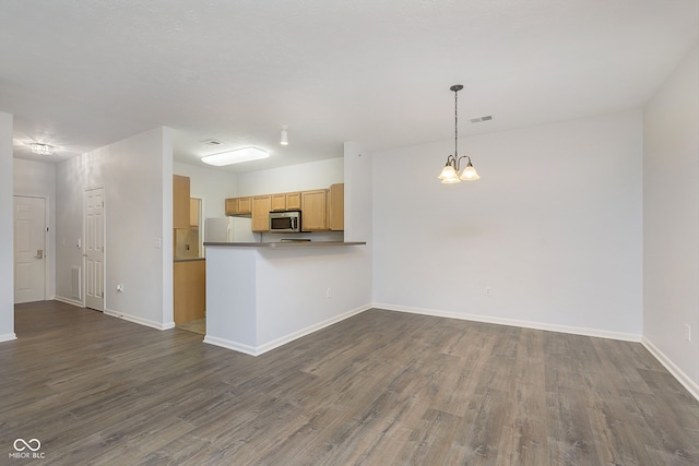 kitchen with light brown cabinets, dark wood-type flooring, a notable chandelier, white fridge, and pendant lighting