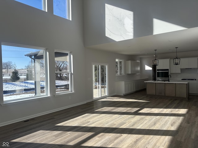 unfurnished living room featuring a towering ceiling and dark hardwood / wood-style floors