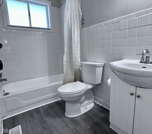 full bathroom featuring washtub / shower combination, toilet, wood-type flooring, tile walls, and vanity