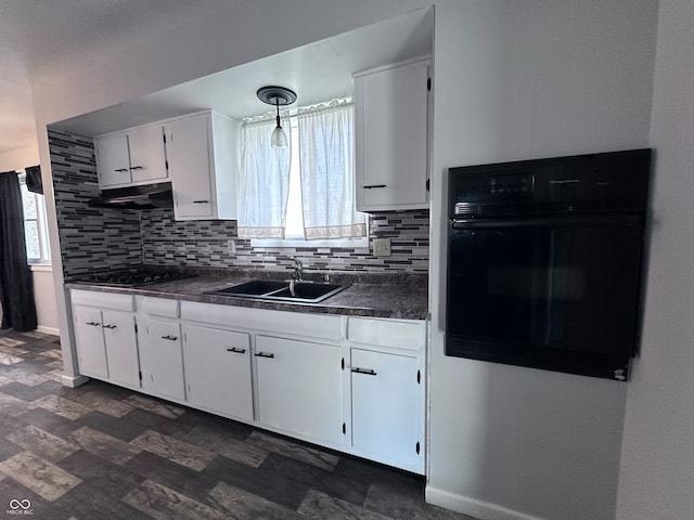 kitchen with pendant lighting, sink, tasteful backsplash, black appliances, and white cabinets