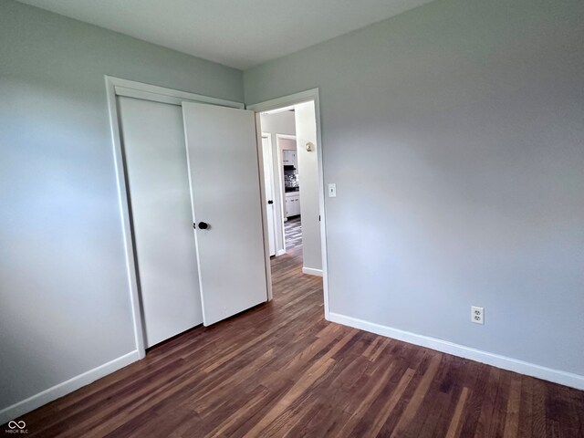 unfurnished bedroom with dark wood-type flooring and a closet