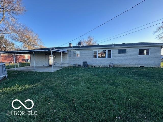 back of property with central AC unit, a patio area, and a lawn