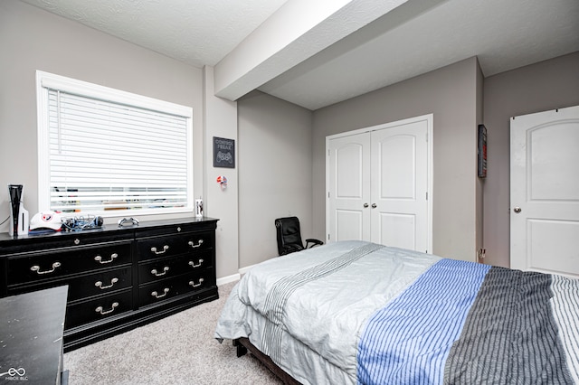 carpeted bedroom with a textured ceiling and a closet