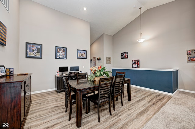 dining space with light hardwood / wood-style floors and high vaulted ceiling