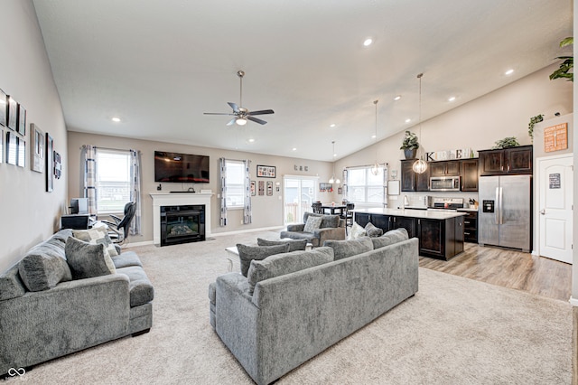 carpeted living room featuring ceiling fan, sink, and high vaulted ceiling