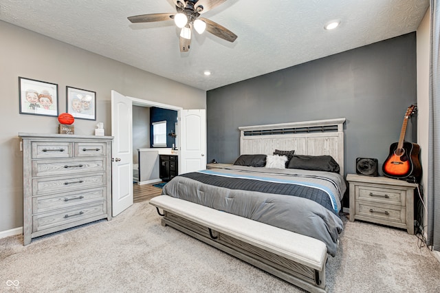 carpeted bedroom featuring ceiling fan, a textured ceiling, and ensuite bath