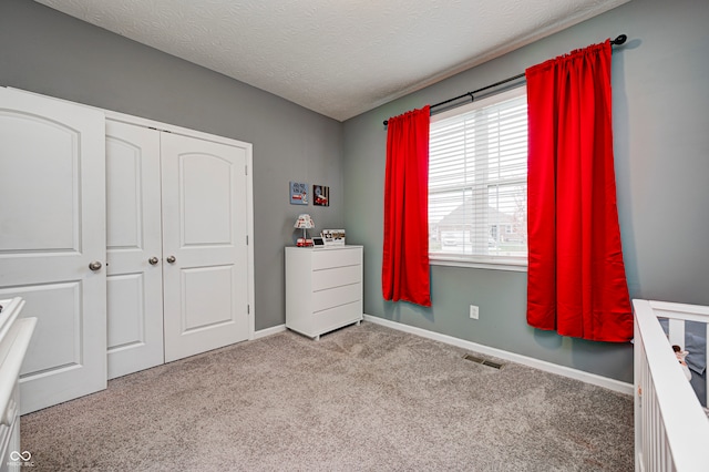 unfurnished bedroom featuring light carpet, a textured ceiling, and a closet