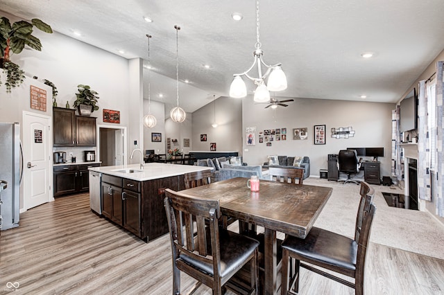 dining space featuring a textured ceiling, ceiling fan, sink, light hardwood / wood-style flooring, and lofted ceiling