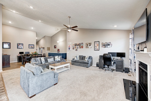 living room with a textured ceiling, hardwood / wood-style flooring, high vaulted ceiling, and ceiling fan