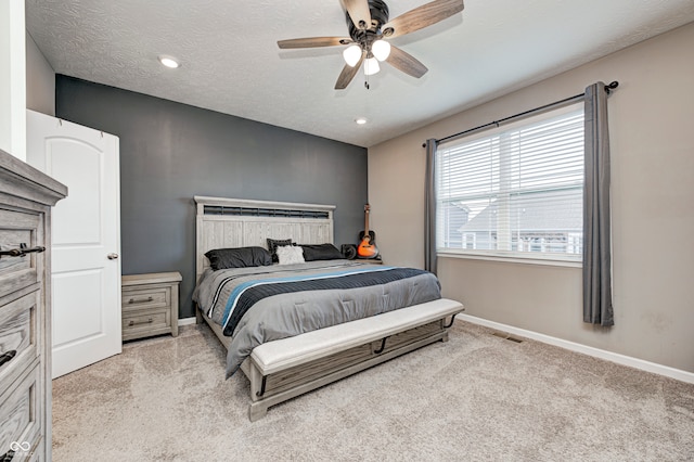 bedroom with a textured ceiling, light colored carpet, and ceiling fan