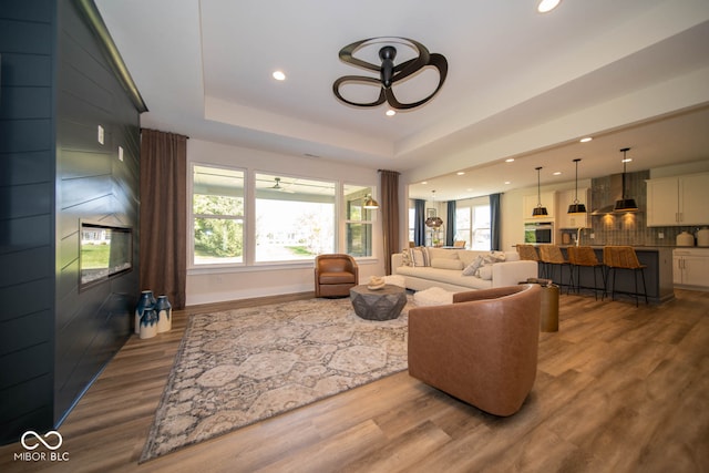 living room featuring a raised ceiling, hardwood / wood-style flooring, and ceiling fan