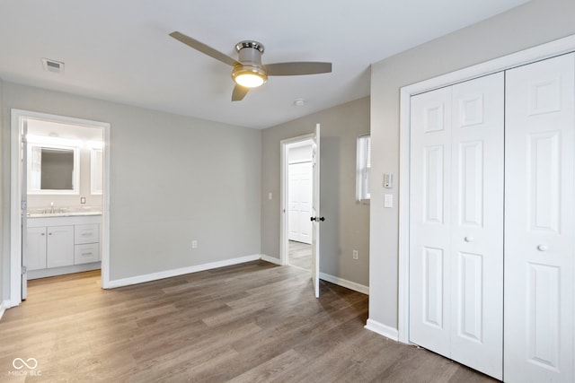 unfurnished bedroom with ceiling fan, sink, ensuite bathroom, light hardwood / wood-style floors, and a closet