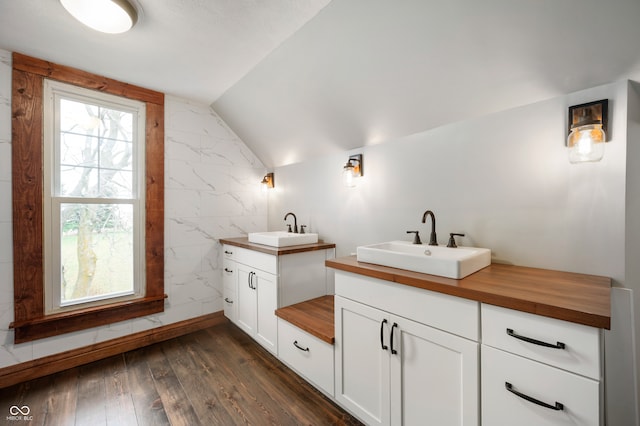 bathroom with tile walls, hardwood / wood-style flooring, vanity, and lofted ceiling