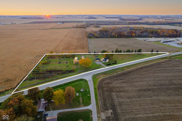 aerial view at dusk featuring a rural view and a water view
