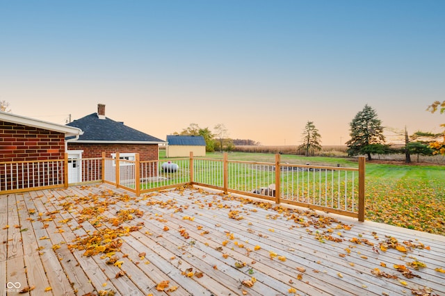 deck at dusk featuring an outdoor structure and a yard