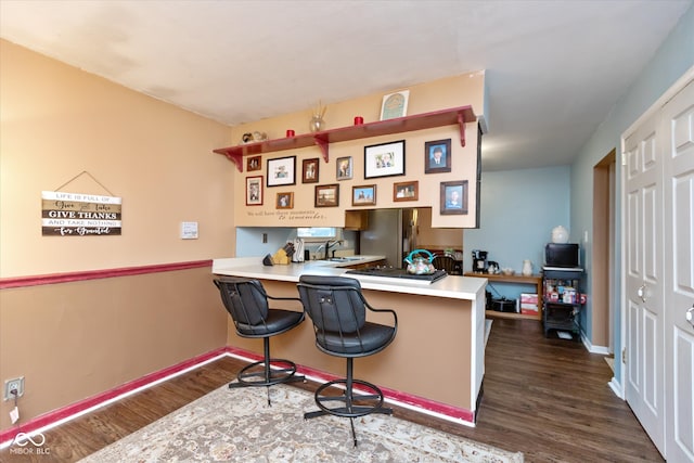 home office with dark hardwood / wood-style flooring, built in desk, and sink