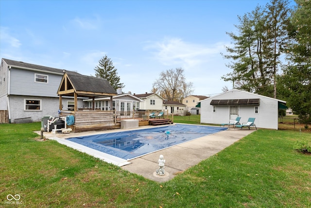 view of pool with a lawn, a wooden deck, and an outbuilding