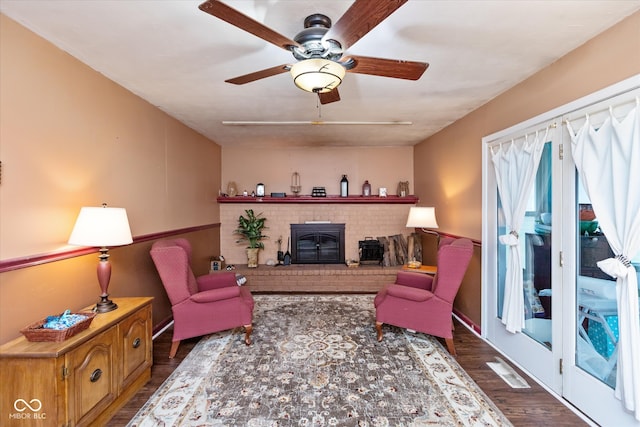 living room featuring ceiling fan, a wood stove, and dark wood-type flooring