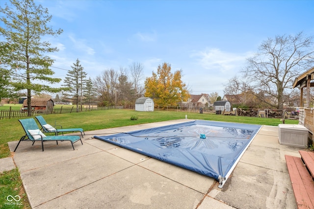 view of pool with a lawn, a patio, and a shed