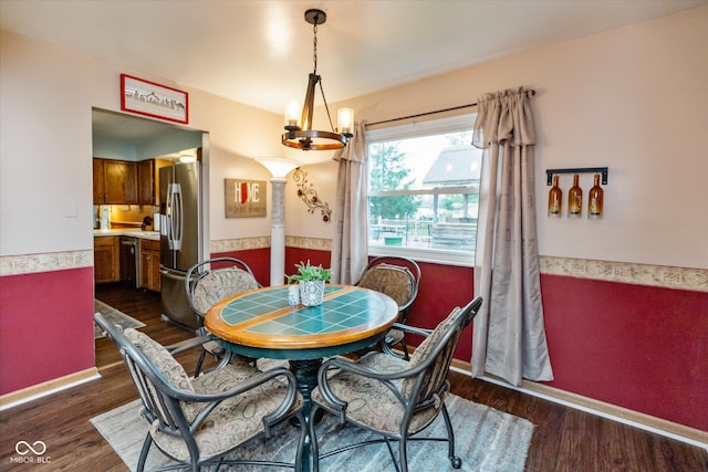 dining room with dark wood-type flooring and an inviting chandelier