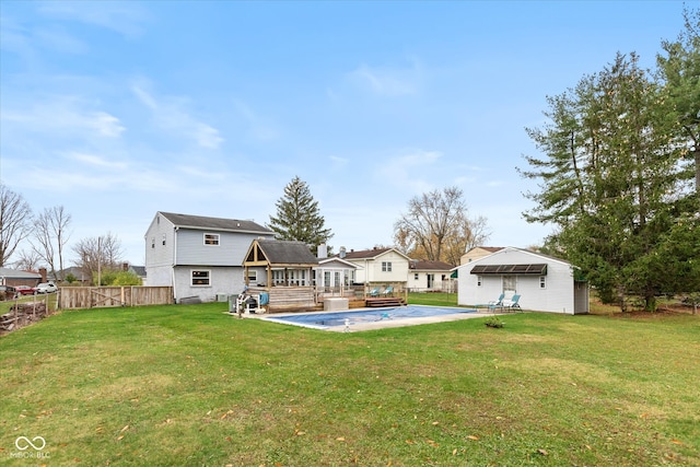 rear view of house with a lawn, an outbuilding, and a wooden deck