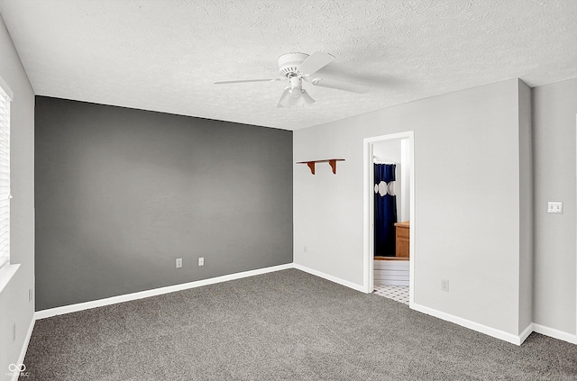 spare room featuring ceiling fan, dark carpet, and a textured ceiling