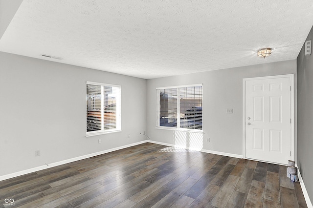 empty room with dark hardwood / wood-style floors and a textured ceiling