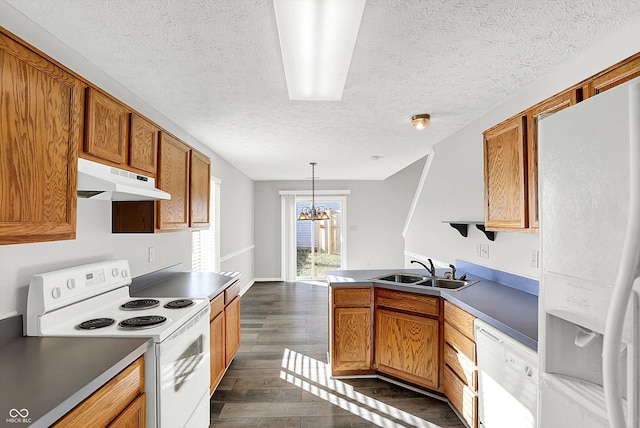 kitchen featuring sink, dark wood-type flooring, an inviting chandelier, pendant lighting, and white appliances